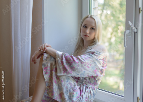 Beautiful young woman sitting by the window. Selective focus.