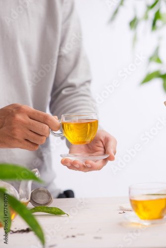 Hand holding cup of tea on wooden table background