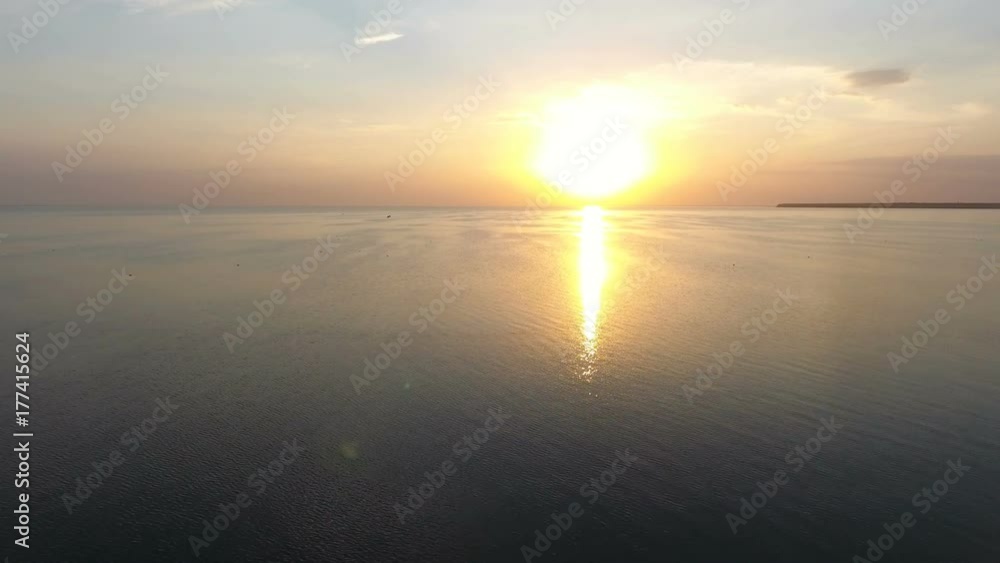 An encouraging bird`s eye shot of shining sea waters at a picturesque sunset on a sunny day in summer. The drifting waves are covered with a romantic sun path. The skyscape is multicolored. An encouraging bird`s eye shot of shining sea waters at a picturesque sunset on a sunny day in summer. The drifting waves are covered with a romantic sun path. The skyscape is multicolored.