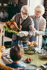 grandfather putting turkey on thanksgiving table