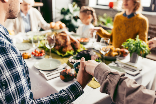 Фотография family holding hands and praying on thanksgiving