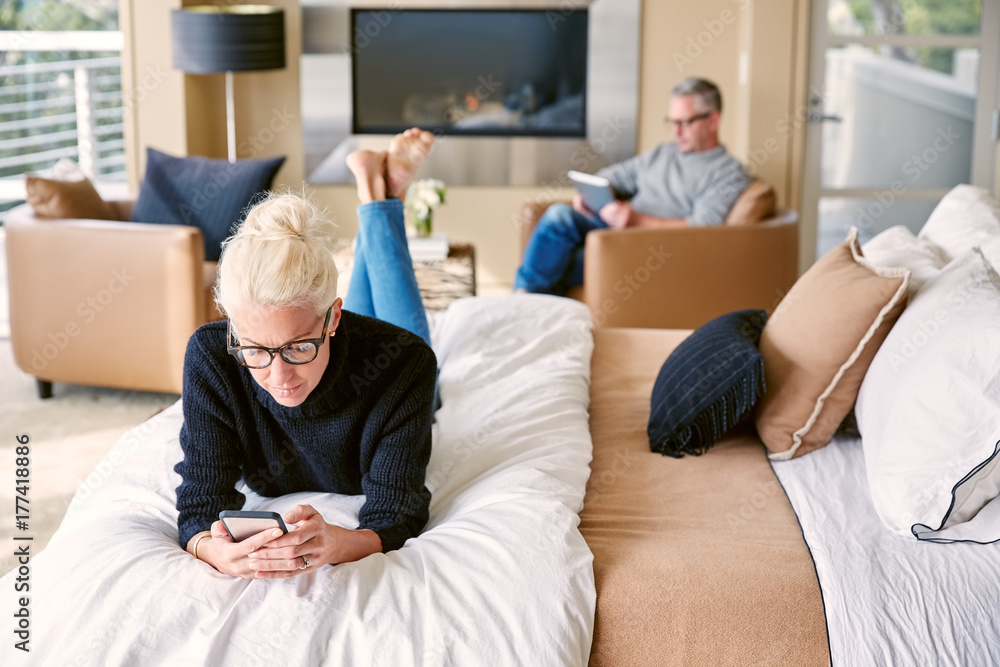 Couple relaxing in luxury bedroom at home with technology Couple relaxing in luxury bedroom at home with technology