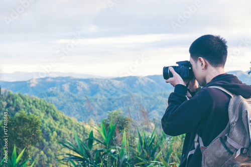 Nature photographer tourist with camera shoots while standing on top of the mountain