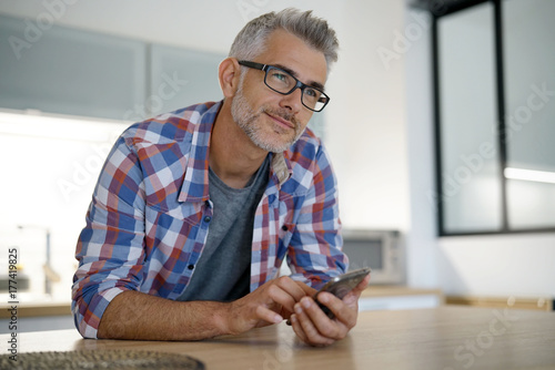 Middle-aged man at home using smartphone