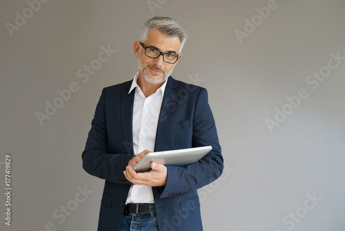 Trendy businessman using tablet, isolated photo
