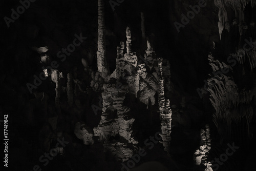Spéléologie dans une grotte avec stalagmites et stalagmites dans la pénombre dans une salle cathédrale d'une caverne. © fred.do.photo