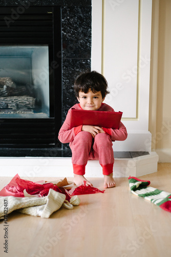 a little boy hugs his wrapped christmas present