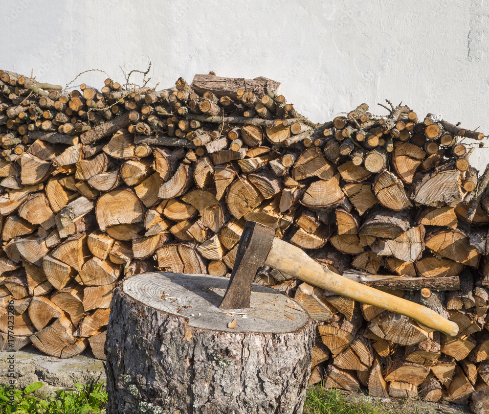 axe on the chopping block with chopped wood pile leveled on white wall axe on the chopping block with chopped wood pile leveled on white wall