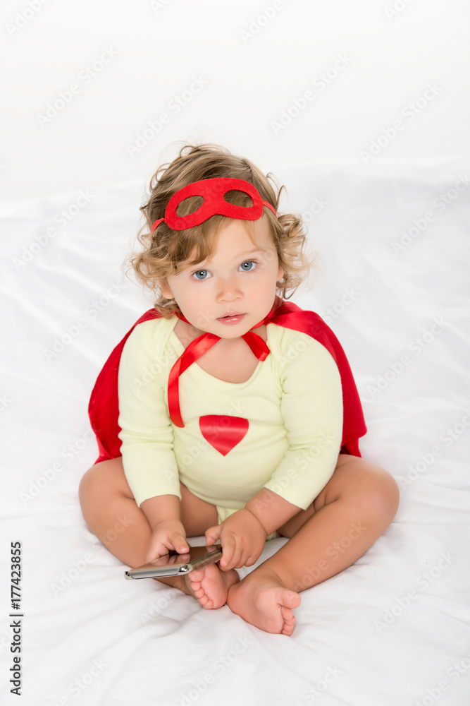 toddler in superhero costume with smartphone toddler in superhero costume with smartphone