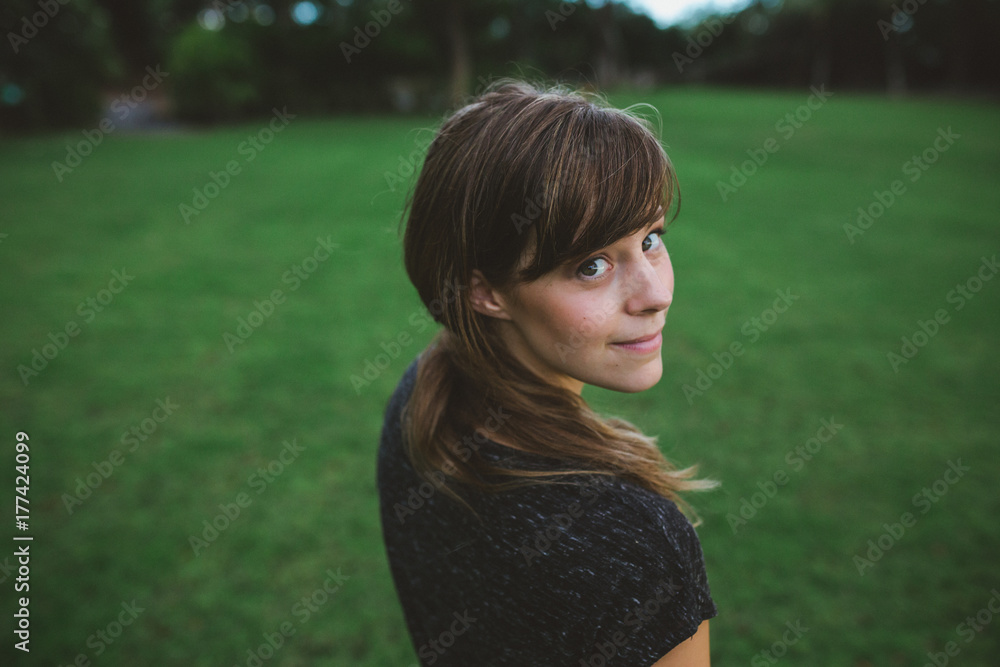 Pretty girl in grey dress looking back at camera on grass field Pretty girl in grey dress looking back at camera on grass field