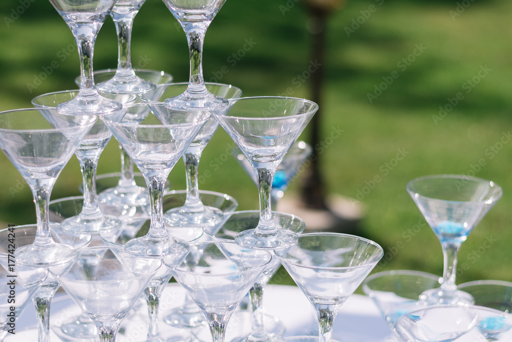 Champagne glass pyramid. Pyramid of glasses of wine, champagne, tower of champagne's glass in wedding reception party. Summertime, green grass background Champagne glass pyramid. Pyramid of glasses of wine, champagne, tower of champagne's glass in wedding reception party. Summertime, green grass background