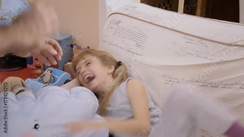 A dad tickling his daughter on the sofa. Bonding, happy family, fun times.
