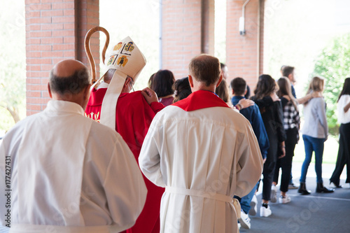 Vescovo che si avvia verso la chiesa con i suoi fedeli per la cresima photo