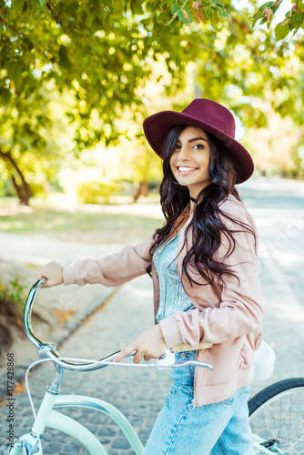 woman in hat standing with bicycle
