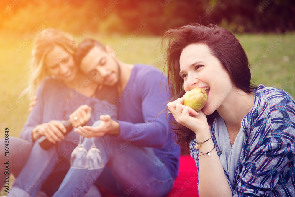 woman eating pear with friends at picnic woman eating pear with friends at picnic