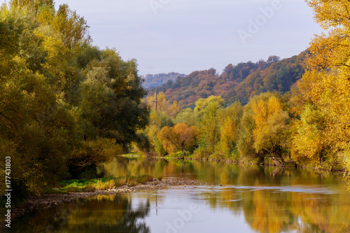 Autumn colorful foliage over lake with beautiful woods in red and yellow color.