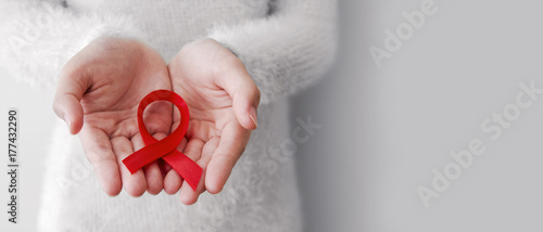 Red ribbon on woman hands for world aids day with copy space