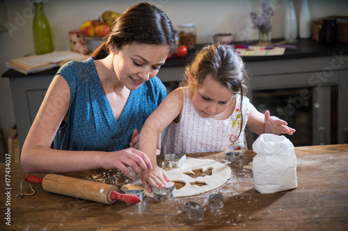 A mom and her little daughter preparing pastry in the kitchen.