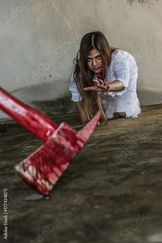 Fototapeta Naklejka Na Ścianę i Meble -  Zombie woman crawling on the floor and axe with bloody