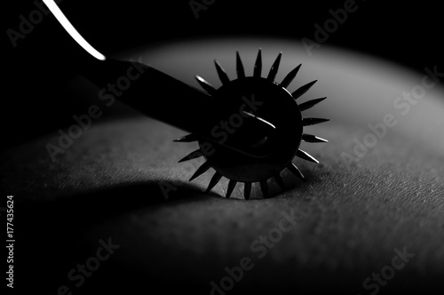 BDSM nude submissive woman act with Wartenberg wheel photo