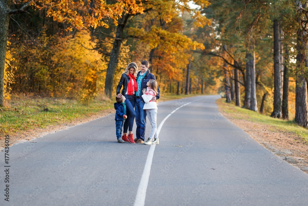 A happy family having fun in autumn forest. family with children walking in the park. Mother and father with son and daughter resting and hugging outdoors in fall with 