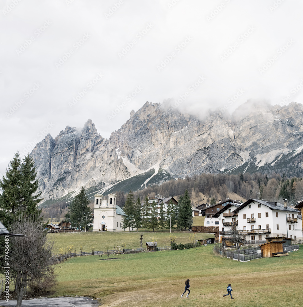 Two kids running together in the distance in a beautiful mountain town Two kids running together in the distance in a beautiful mountain town