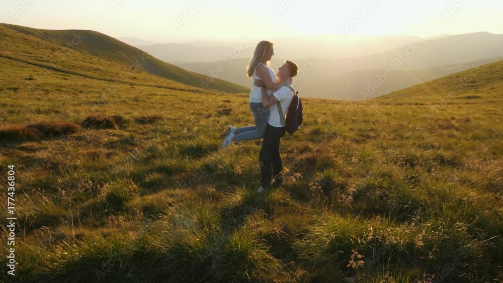 A loving couple, a man standing with a woman and raises her up on meadow. A loving couple, a man standing with a woman and raises her up on meadow.