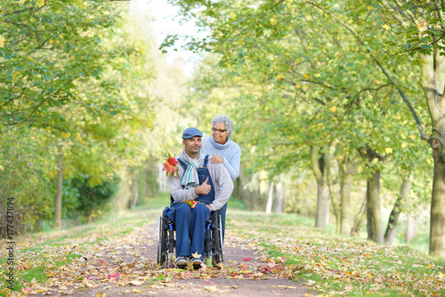 helfen - ältere Frau und junger Mann im Rollstuhl