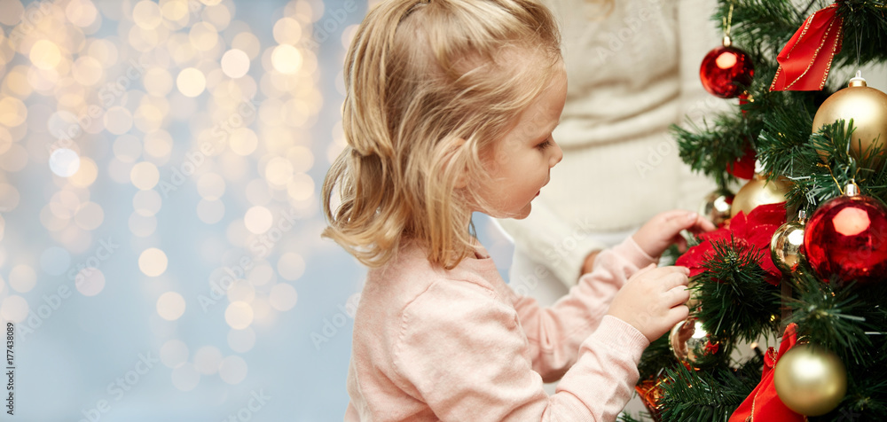 close up of little girl decorating christmas tree