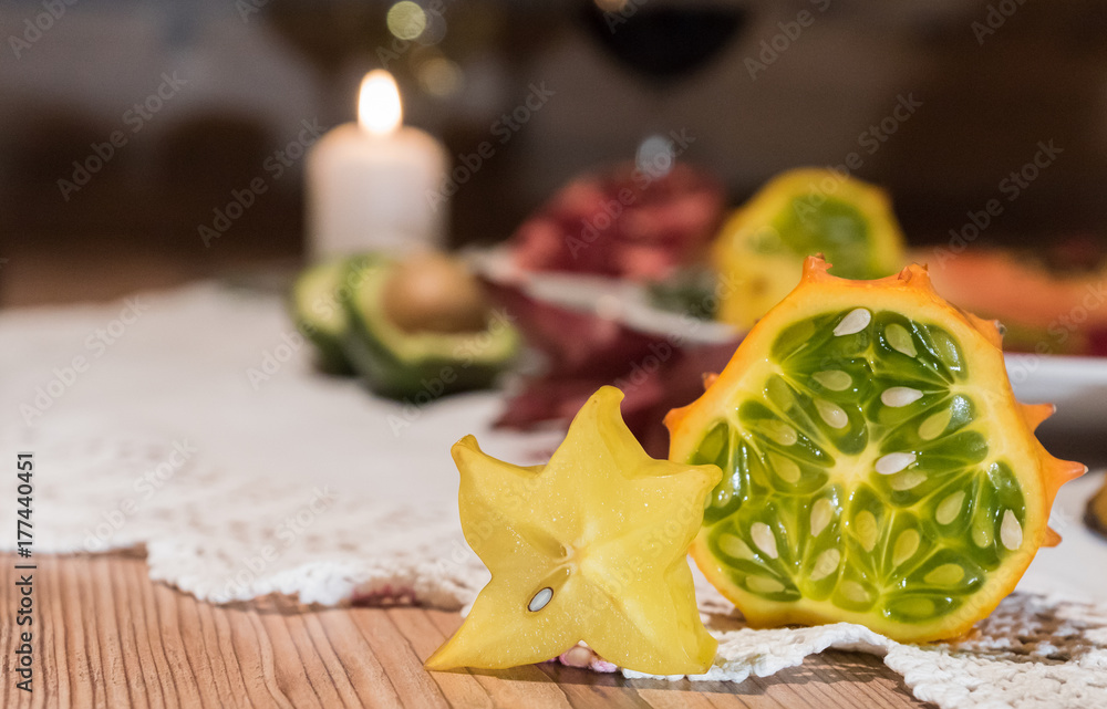 Sternfrucht und Kiwano mit Kerzenlicht im Hintergrund