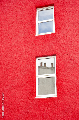 fachada de pared pintada de rojo con ventanas de color blanco