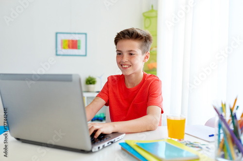 student boy typing on laptop computer at home