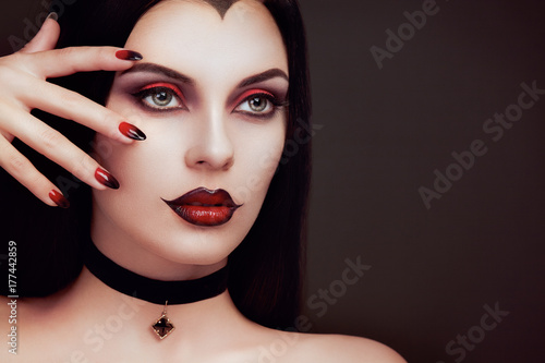 Halloween Vampire Woman portrait. Beautiful Glamour Fashion Sexy Vampire Lady with long dark Hair  beauty make up and Costume