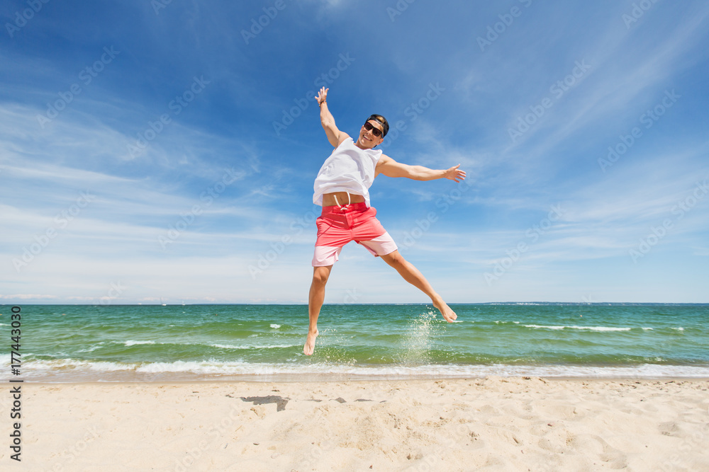 smiling young man jumping on summer beach smiling young man jumping on summer beach
