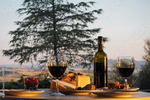 a dinner with wine, bread and cheese at a covered table in the garden