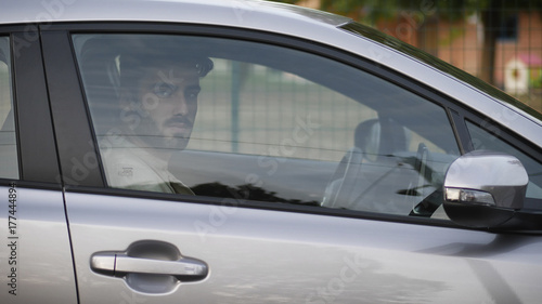 Serious young man or teenager driving car and looking at camera © starsstudio