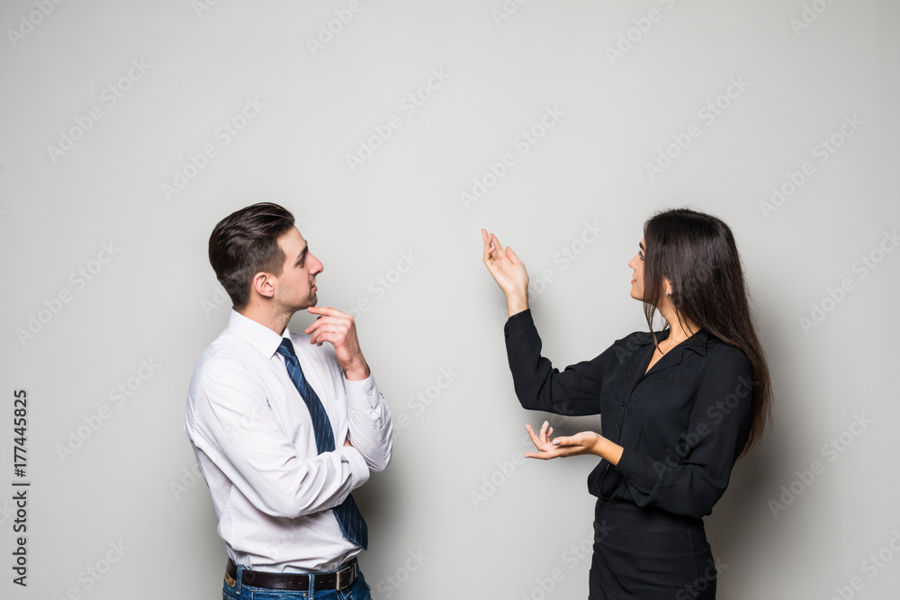 Smiling businesswoman and businessman are conversing against grey background. Smiling businesswoman and businessman are conversing against grey background.
