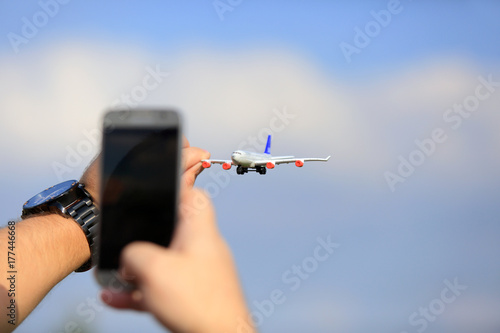 Samolot, zabawka trzymany w palcach, zdjęcie smartfonem.