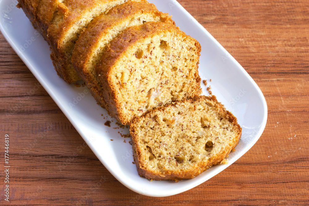 Banana cake. Sliced homemade banana cake on whit plate. Delicious dessert for eat with tea or coffee. Top view on wooden table.