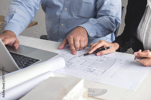 Engineering or Creative architect in construction project, Engineers hands working on construction blueprint and building model at a workplace in office, Building and architecture concept