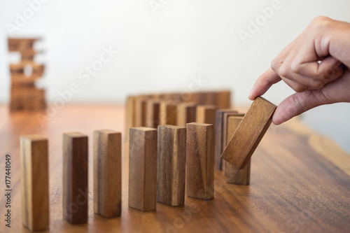 Risk and strategy in business, Close up of businessman hand gambling placing wooden block on a line of domino