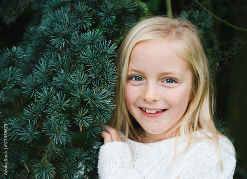 A smiling little girl and a fir tree.