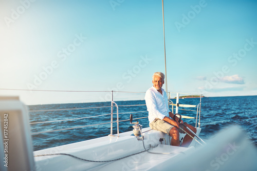 Mature man enjoying a sunny day sailing his boat © Flamingo Images