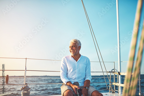 Mature man enjoying a sunny day sailing on the ocean © Flamingo Images
