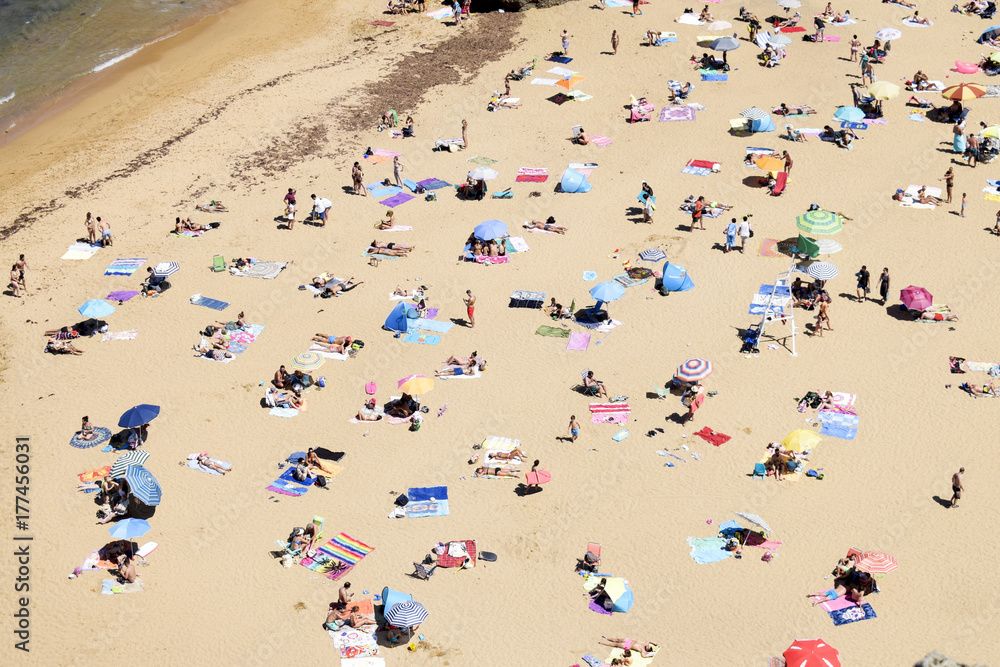 gente con sombrillas tomando el sol en la playa vista desde arriba