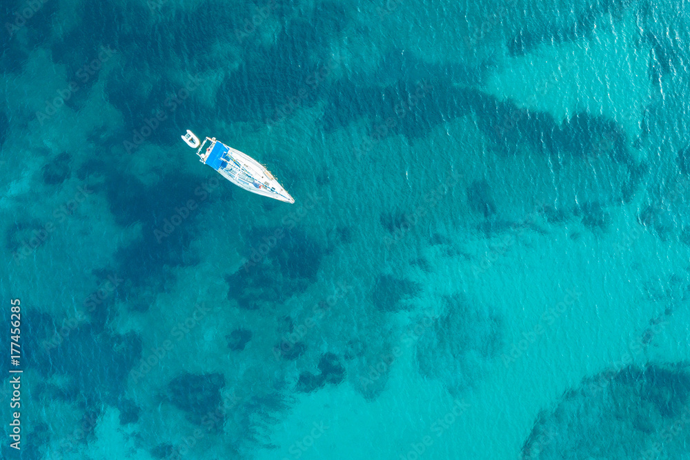 Beautiful beach, coast and bay with crystal clear sea water and a sailing yacht seen from above Beautiful beach, coast and bay with crystal clear sea water and a sailing yacht seen from above