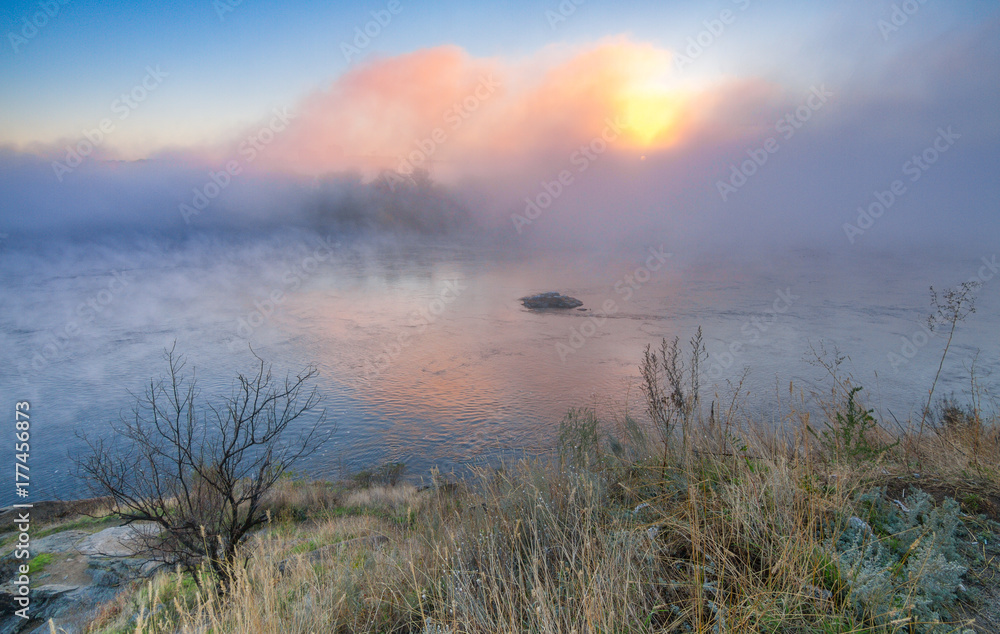 Spectacular fog over the river on dawn in autumn morning