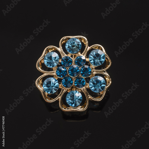 gold round brooch with blue diamonds isolated on black