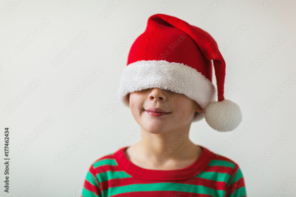 smiling boy with a santa hat pulled over his eyes smiling boy with a santa hat pulled over his eyes