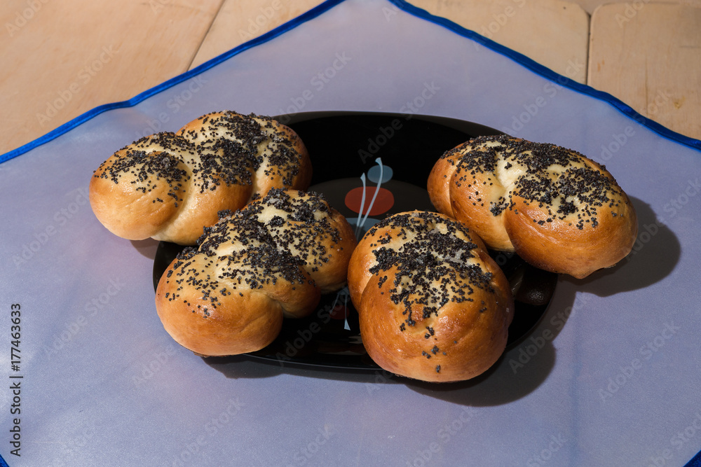 Buns with poppy seeds on a black plate and blue napkin